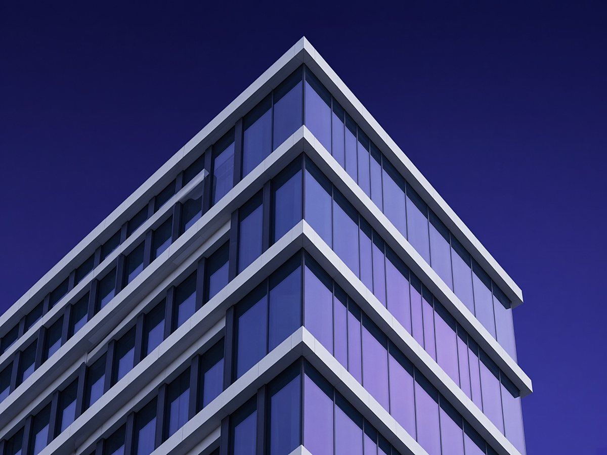 Geometric glass and white facade of a modern tower against a twilight sky